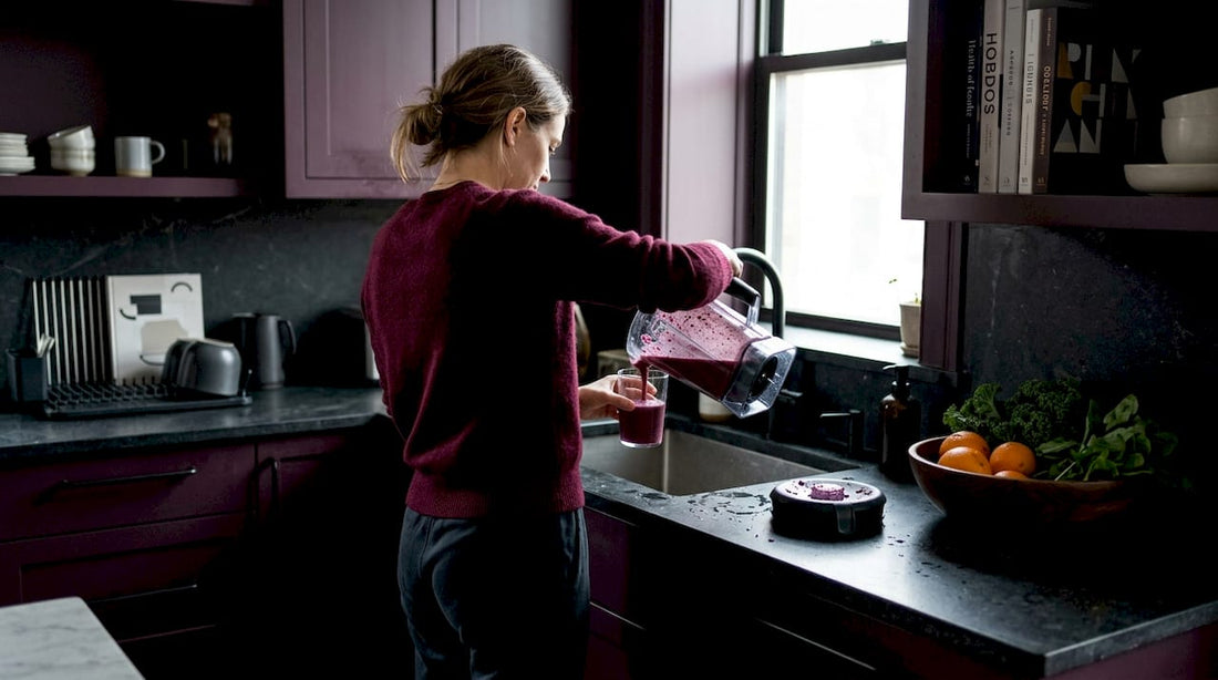 Woman making smoothie in sunlit kitchen