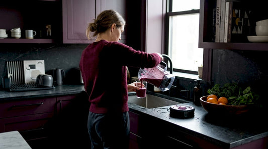 Woman making smoothie in sunlit kitchen