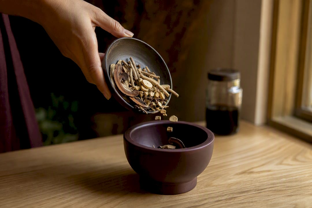 Hand pouring adaptogen herbs into mortar