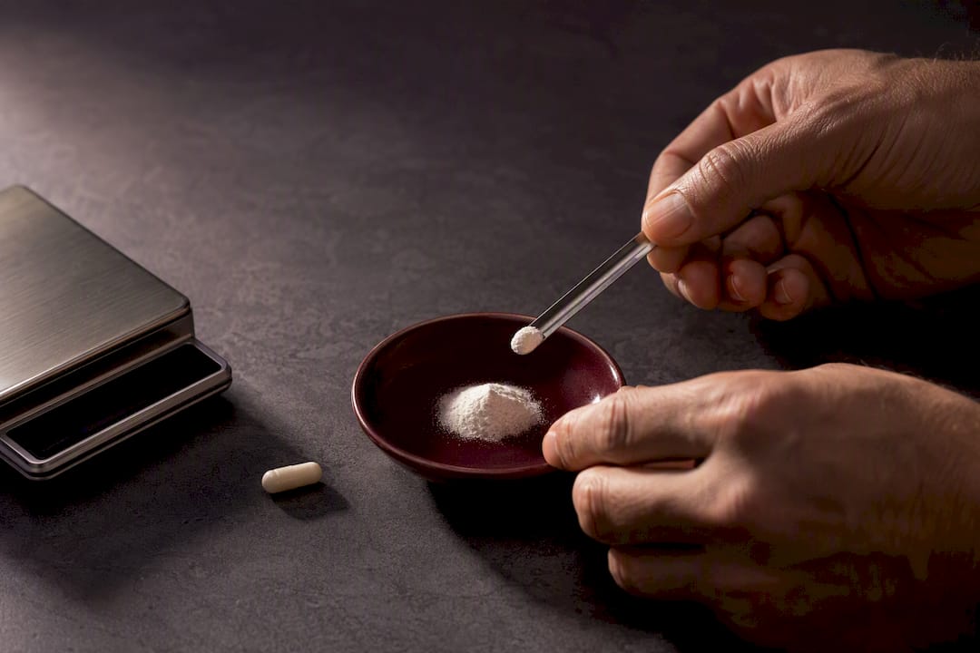 Hands measuring an unbranded supplement dose